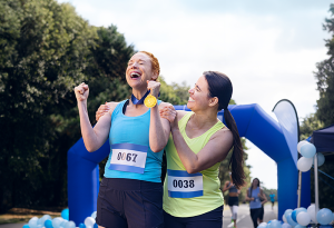 female runner with medal celebrating with friend