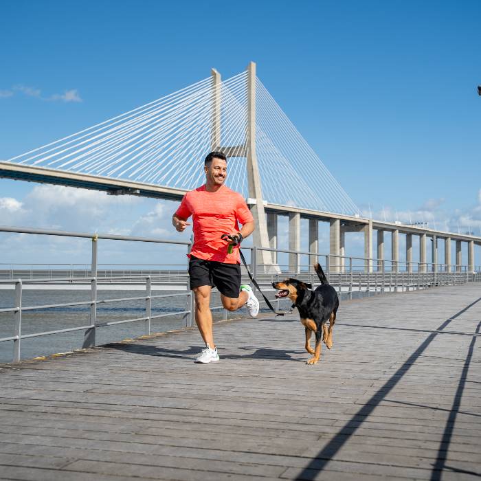 Photo of man running on bridge with dog