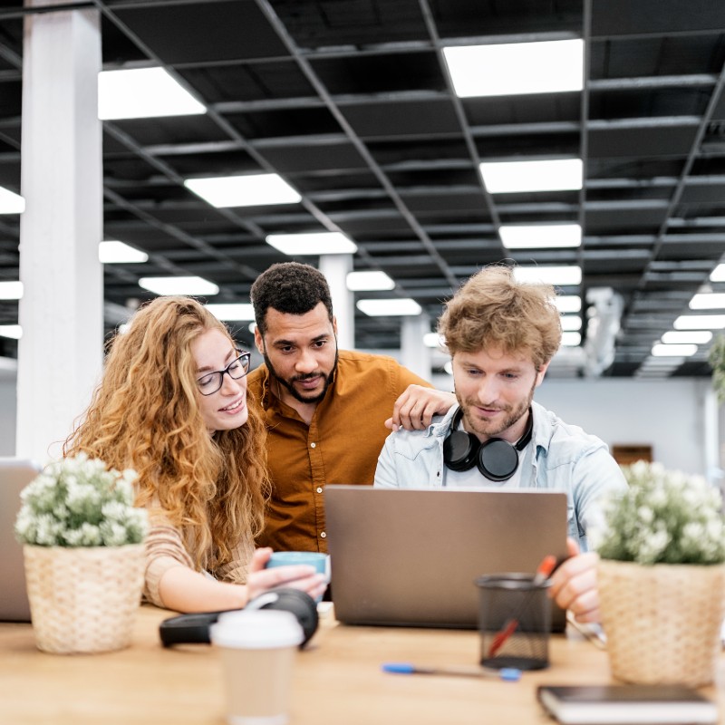 three office workers at desk on laptop