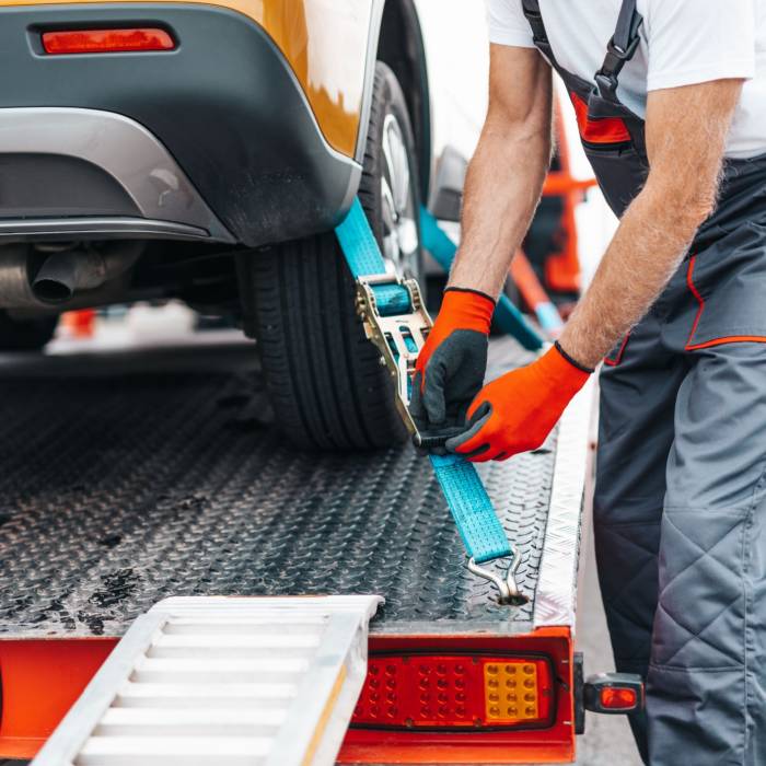 Emergency assistance person securing car to breakdown assistance truck