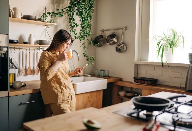 woman with her phone drinking orange juice