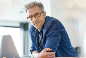 man in blue jacket sitting at computer