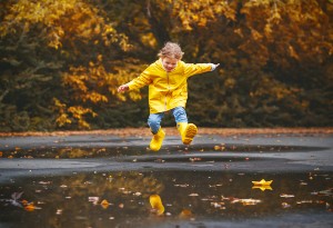 child jumping in puddles