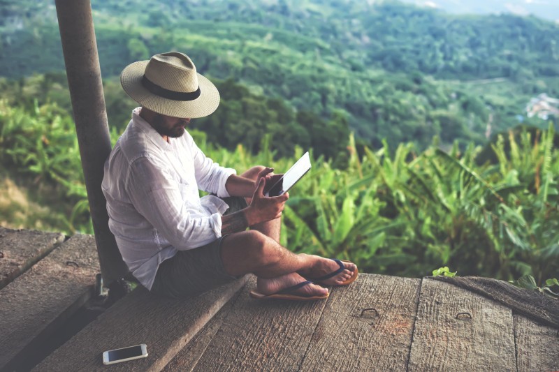 man on tablet in rain forest